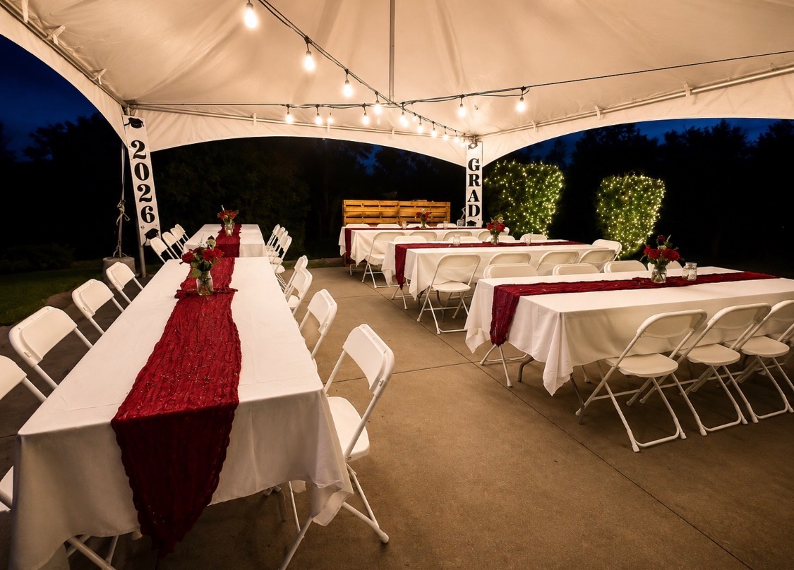 Graduation dinner tables arranged beneath a lighted white event tent