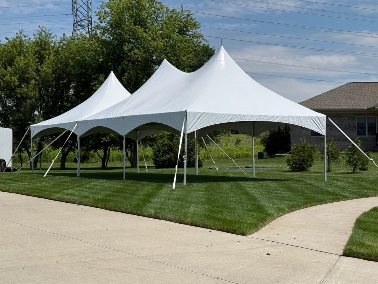 White high-peak event tents set up on a lawn near a driveway